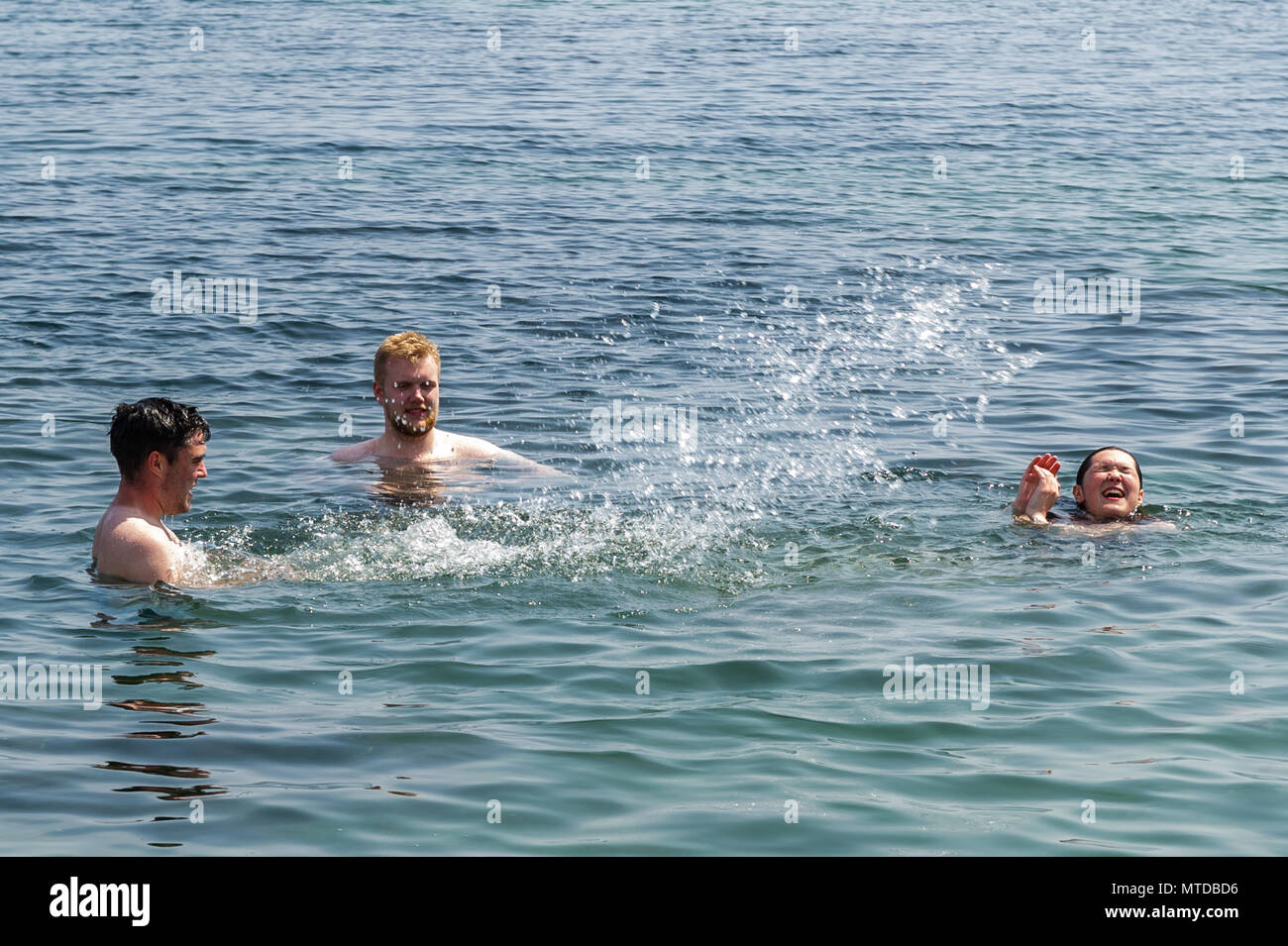 Schull, Ireland. 29th May, 2018.  On the hottest day of the year in West Cork, a group of friends cool off in Schull Harbour. Warm sunshine and highs of up to 27 C will give way to heavy showers and possible thunderstorms later in the day. Credit: Andy Gibson/Alamy Live News. Stock Photo