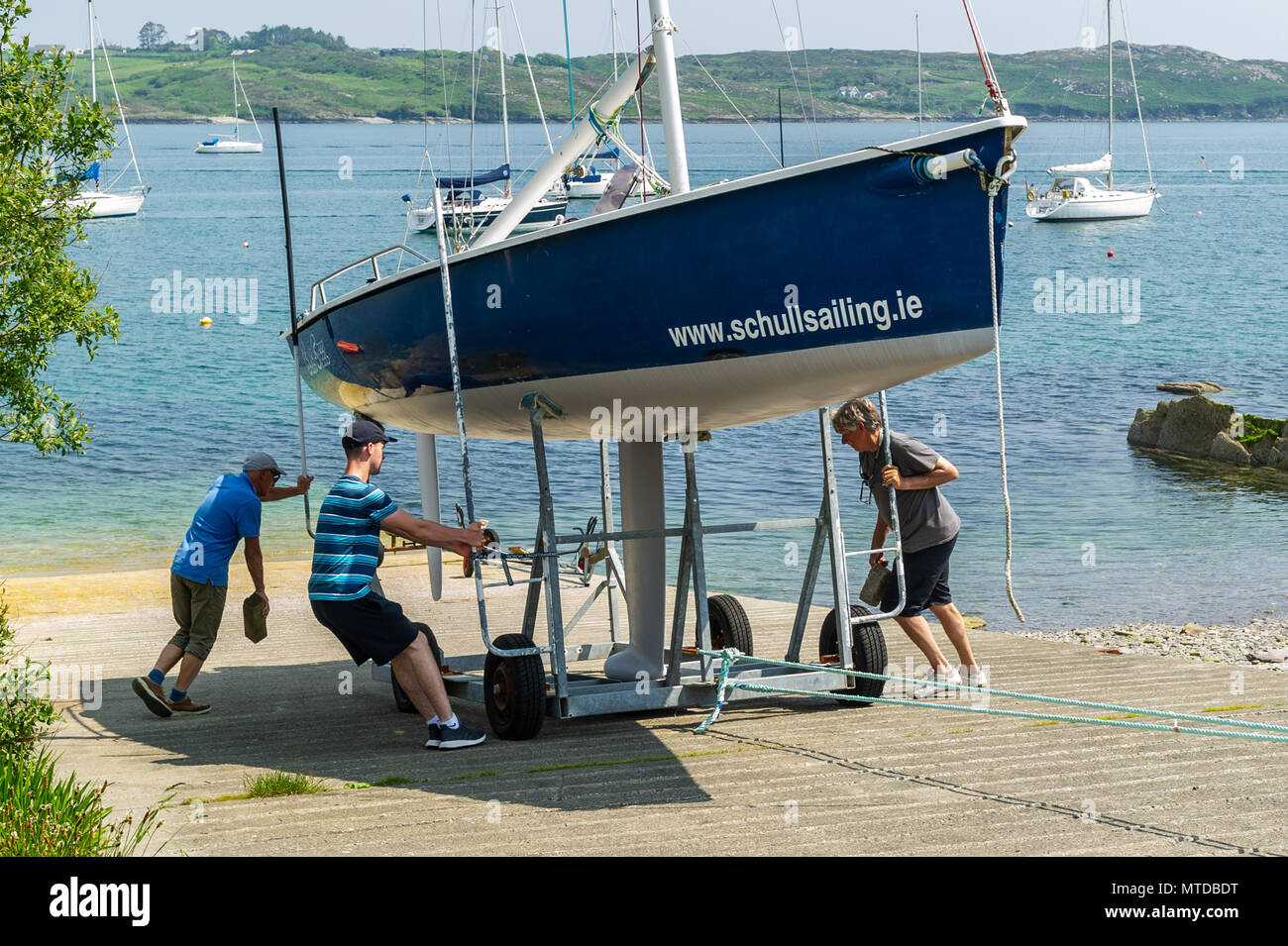 Schull, Ireland. 29th May, 2018.  On the hottest day of the year in West Cork, members of Schull Sailing Club launch a yacht into Schull Harbour. Warm sunshine and highs of up to 27 C will give way to heavy showers and possible thunderstorms later in the day. Credit: Andy Gibson/Alamy Live News. Stock Photo
