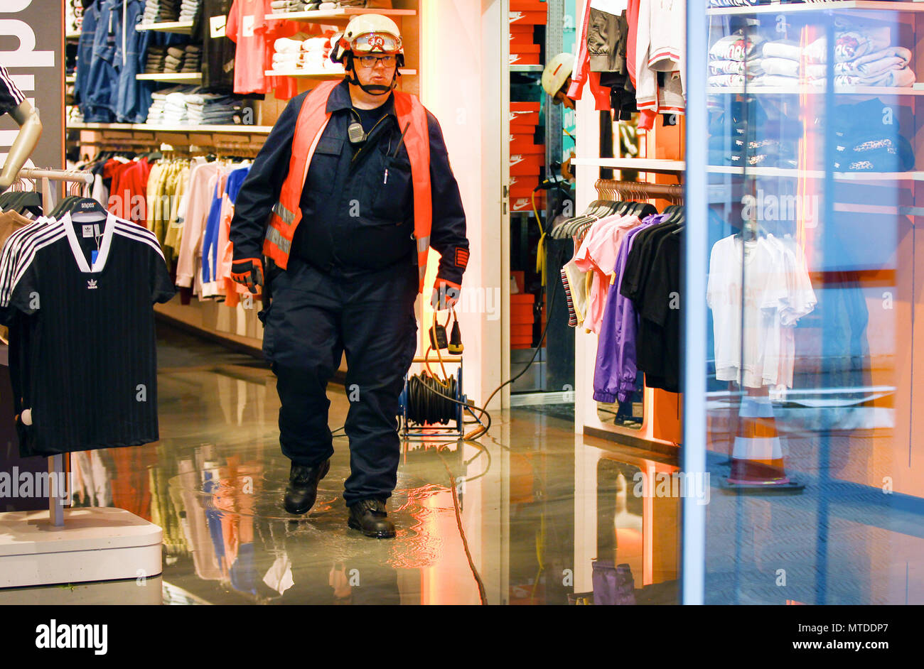 29 May 2018, Germany, Aachen: A firfighter walks through a flooded clothing  store. in a local shopping mall. Strong winds and heavy rainfall has hit  the German state of North Rhine-Westphalia in