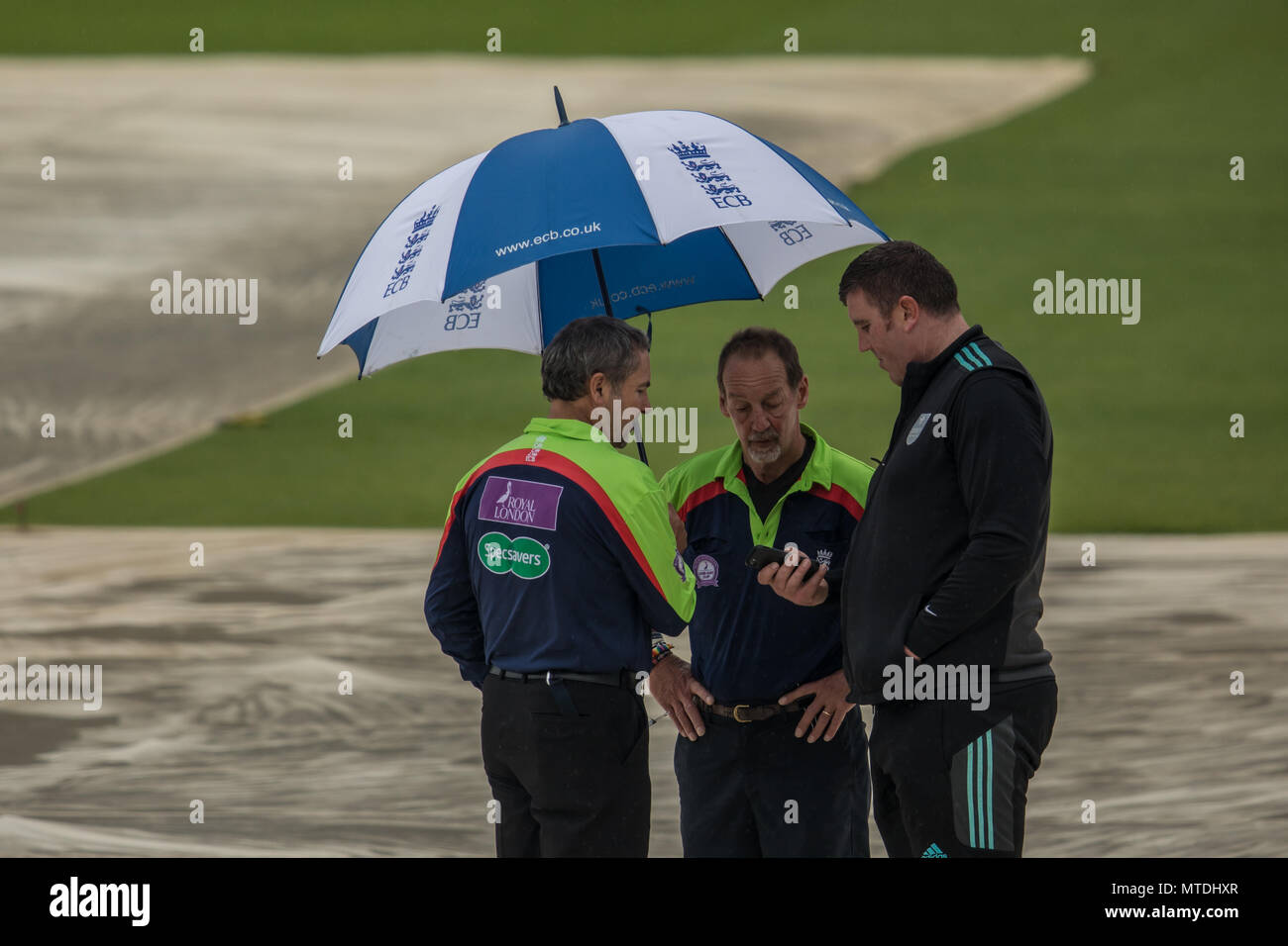 London,UK. 29 May, 2018. Surrey's Head Groundsman, Lee Fortis (right) checks his weather app and it doesn't look good during a pitch inspection  at the Oval with umpires Richard Illingworth (left) & Jeremy Lloyds (centre). The match between Surrey and Sussex in the Royal London One-Day Cup was abandoned without a ball being bowled due to heavy rain in London. David Rowe/Alamy Live News Stock Photo
