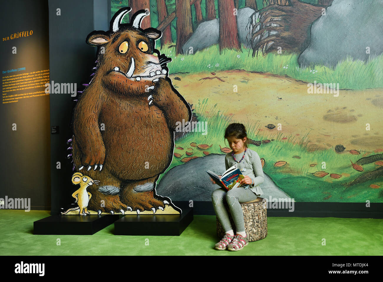 30 May 2018, Germany, Speyer: Valerie reading beside a Gruffalo figure at the exhibition "Das Sams und die Helden der Kinderbuecher" (lit. "Sams and the heroes of childrens' books") at the Historical Museum of Rhineland-Palatinate. The exhibition is running from 01 June 2018 to 06 January 2019. Photo: Uwe Anspach/dpa Stock Photo