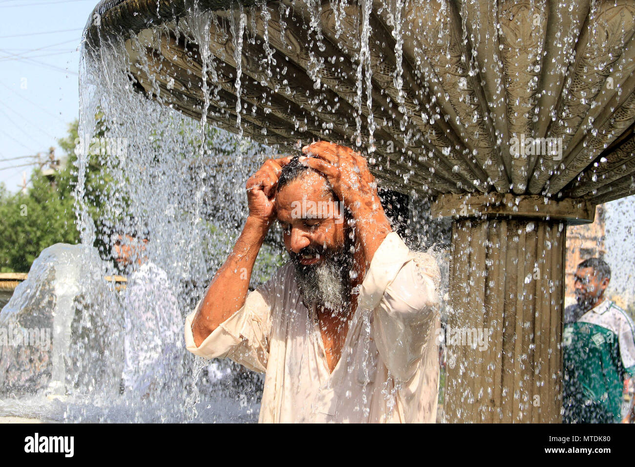 Karachi, Pakistan. 30th May, 2018. A man takes shower to cool off at a