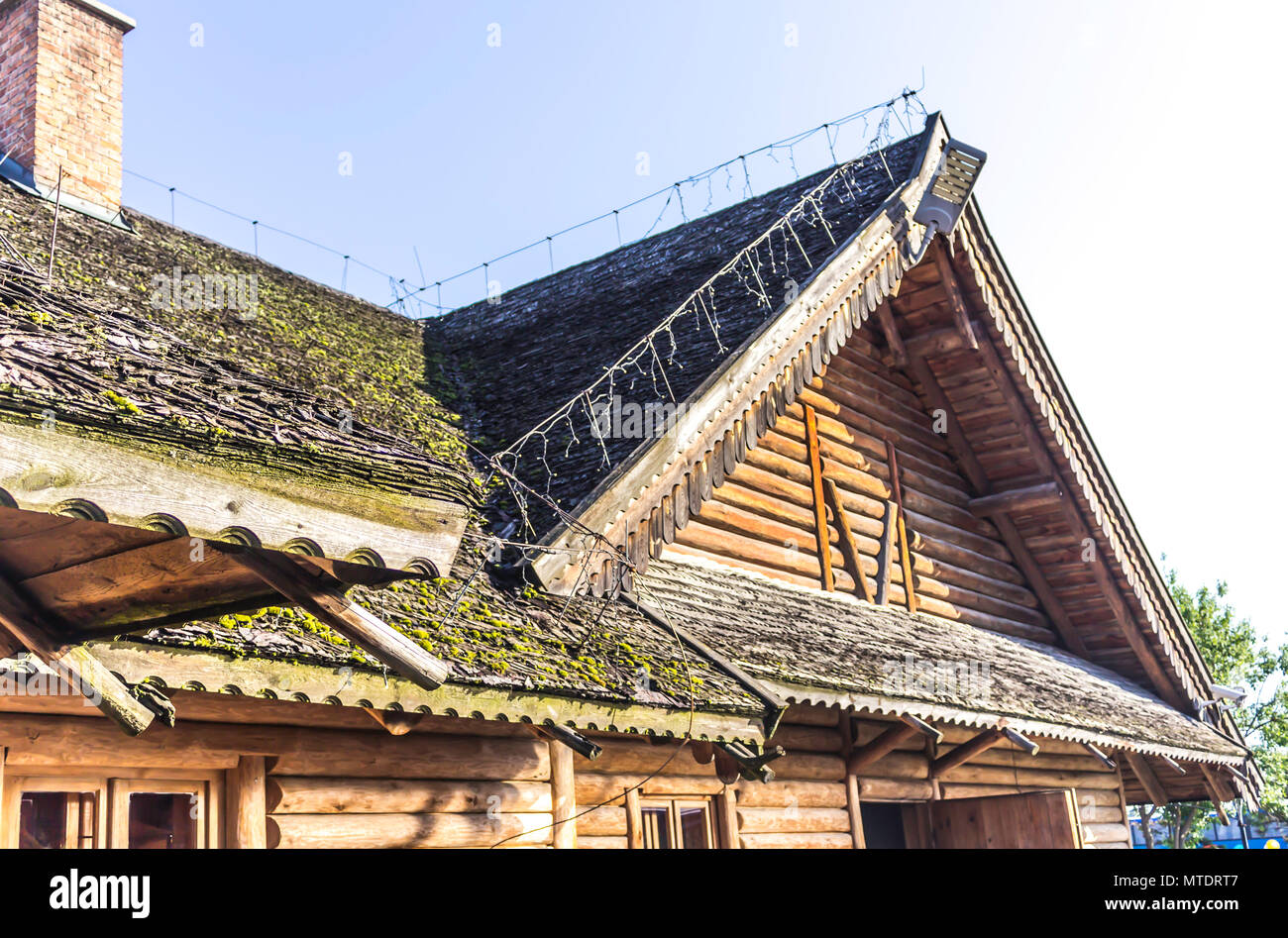 A gable wooden roof. Wooden decoration. The roof is covered with wooden shingles. The pediment