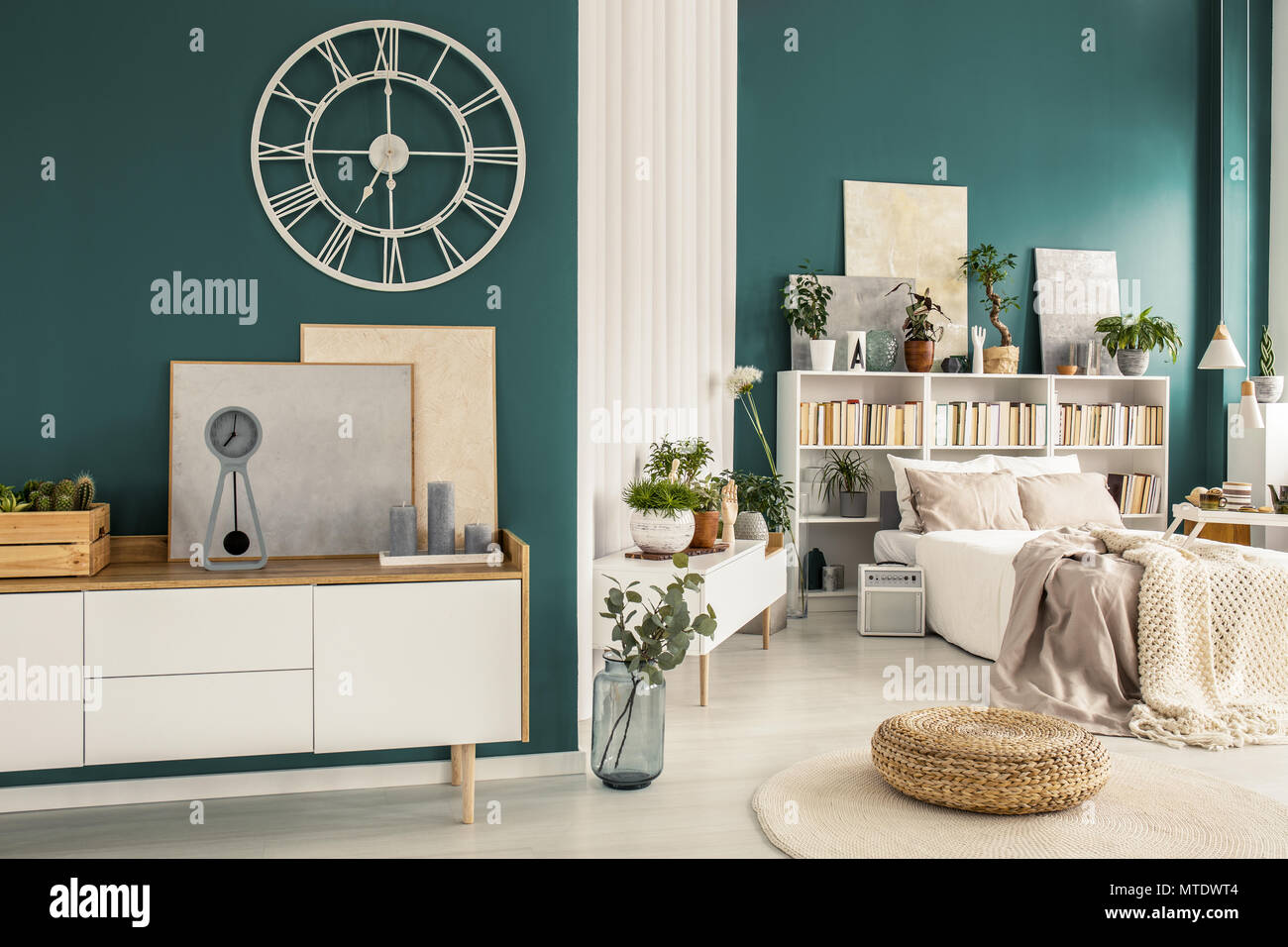 Oldfashioned clock with roman numbers on a turquoise green wall above