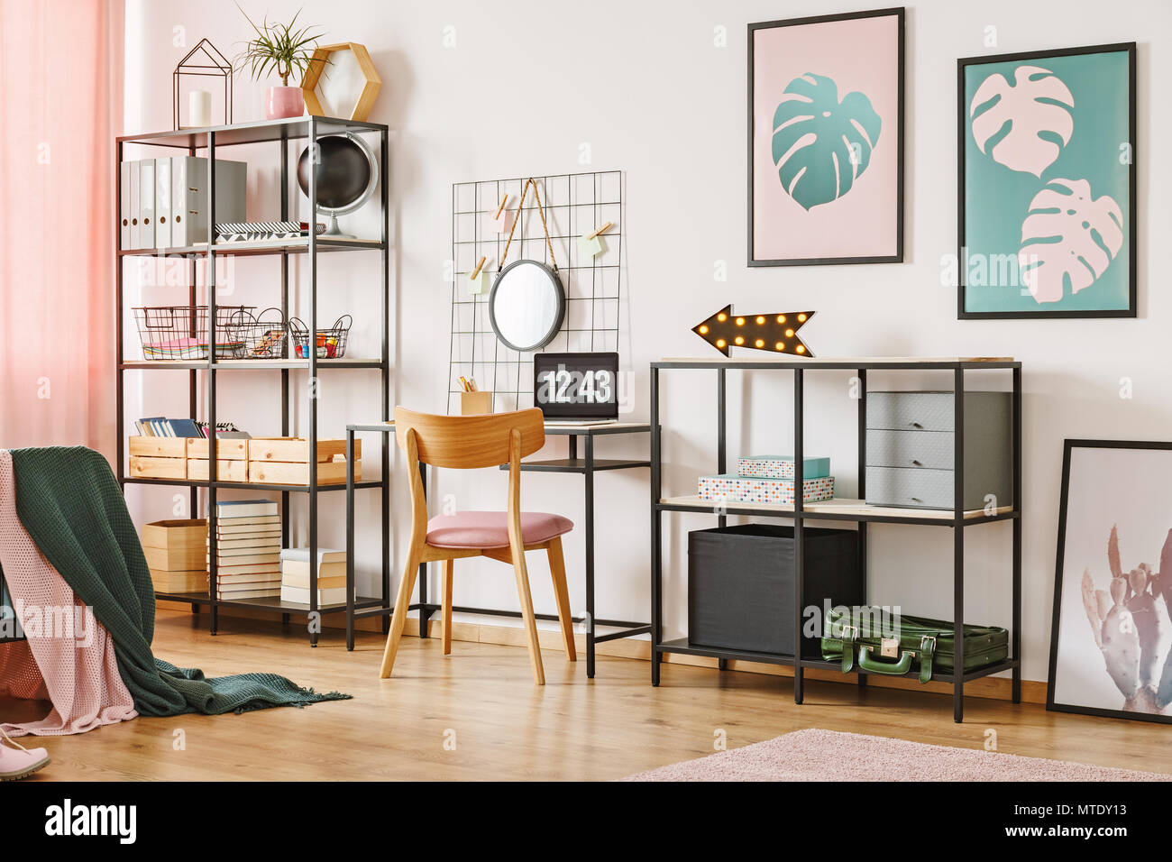 Wooden chair, desk and black shelves with boxes in a pink home office