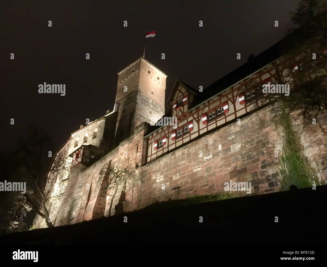 The Heathen Tower of Nuremberg Castle rising into the night sky with the Frankish flag flying Stock Photo