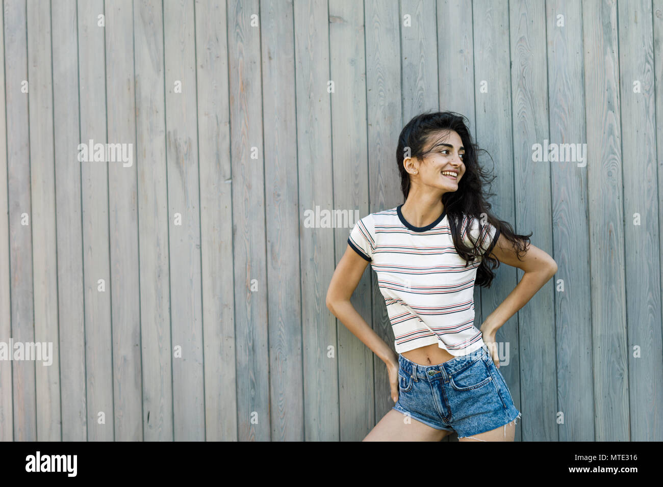 Young happy brunette posing at wall, outdoors shot Stock Photo