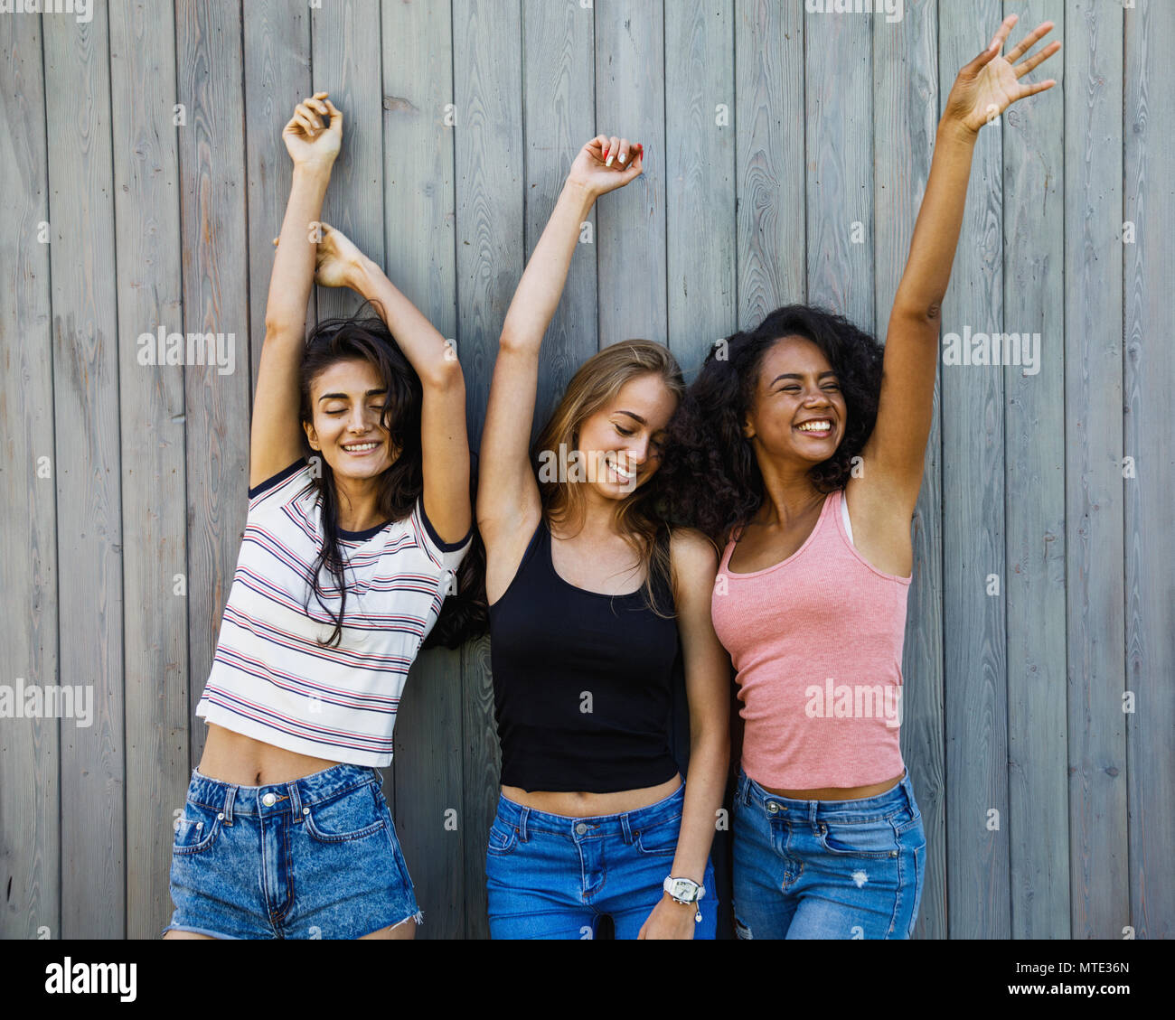 Three young women having fun near wall outdoors Stock Photo