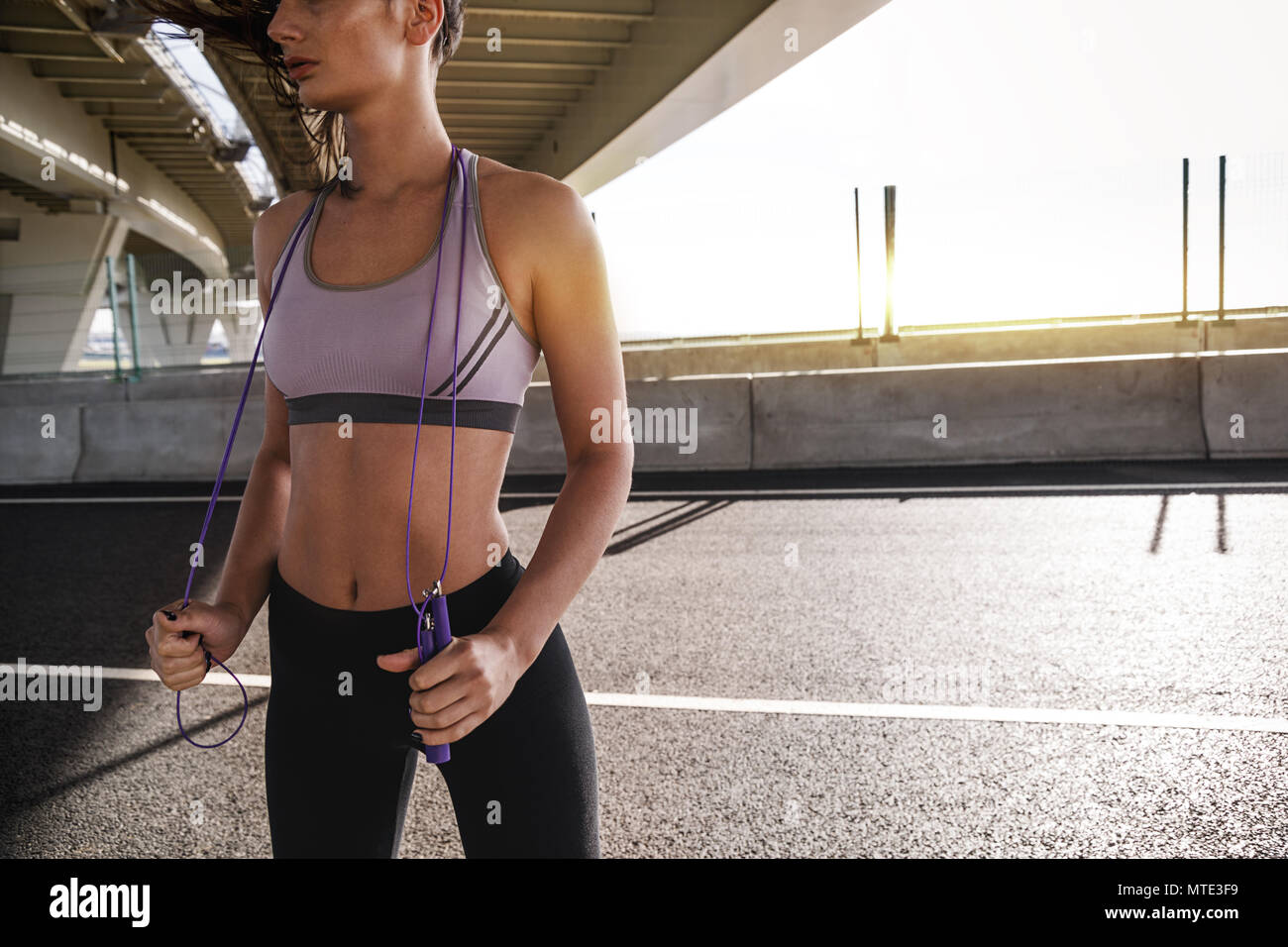 Unrecognizable woman in sports bra with a skipping rope under a bridge  Stock Photo - Alamy