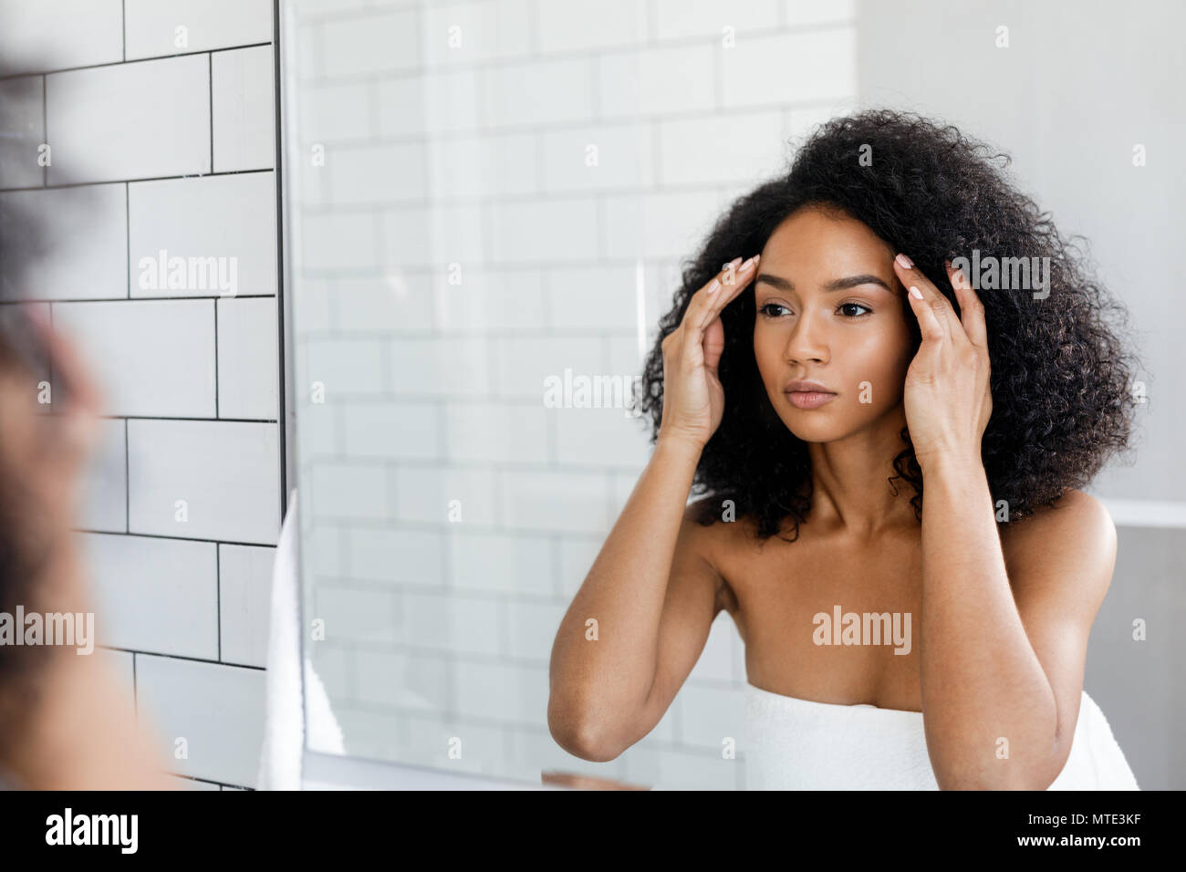 Beautiful woman looking in to mirror, checking her face Stock Photo Alamy