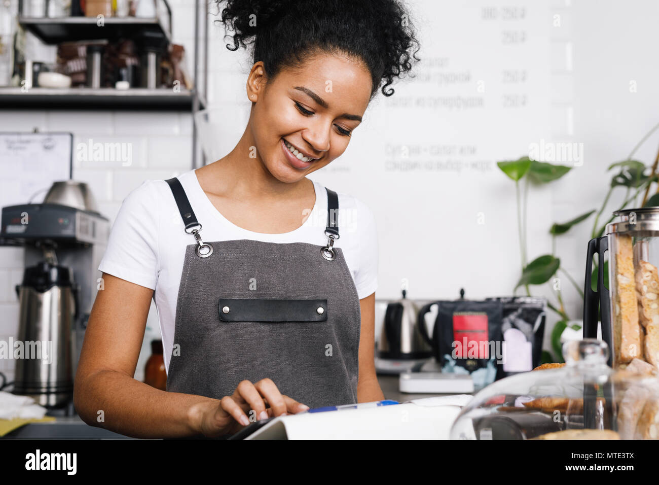 Smiling beautiful waitress using digital tablet in cafe Stock Photo