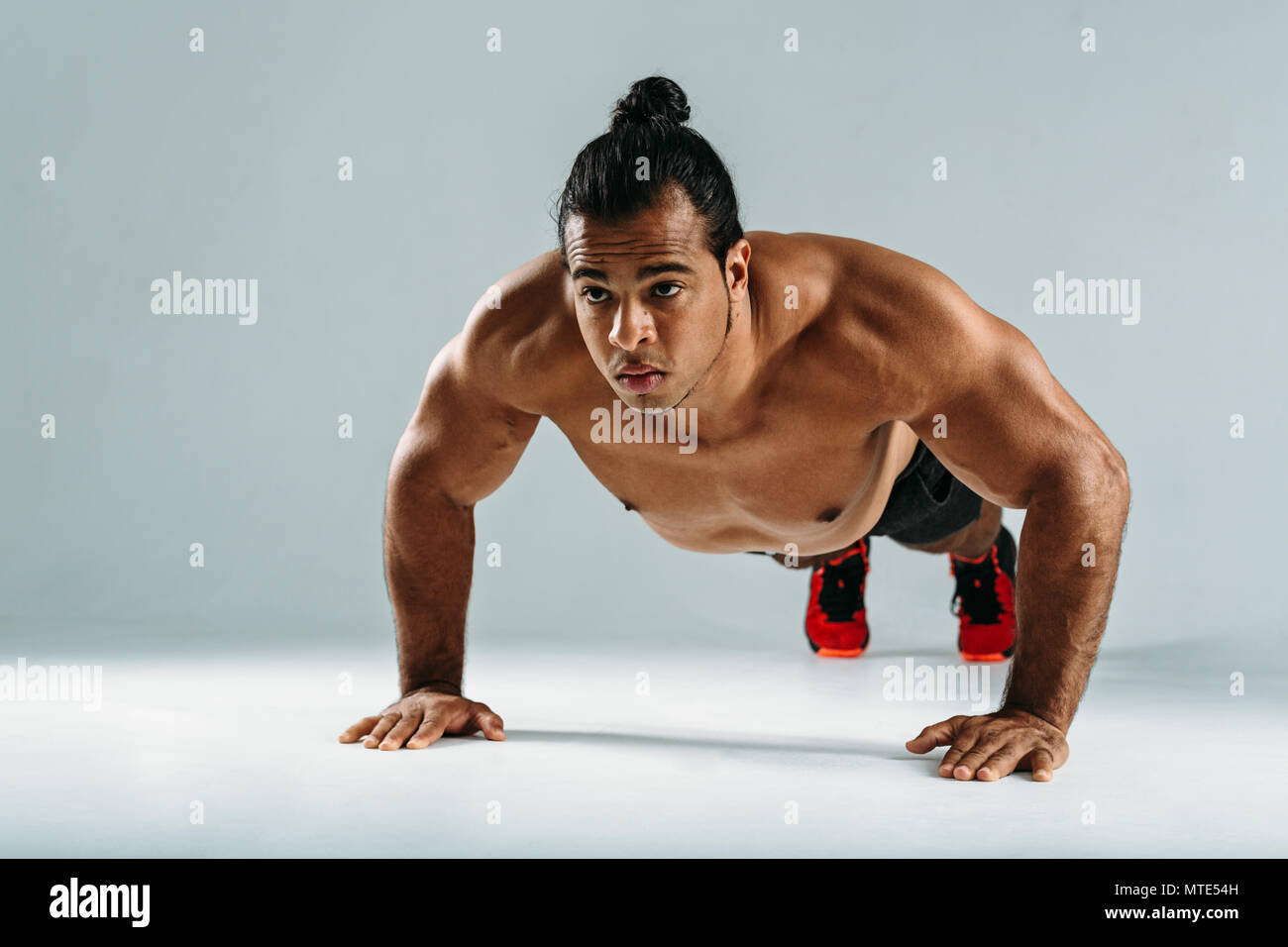 Young man doing push ups in studio on grey background Stock Photo - Alamy
