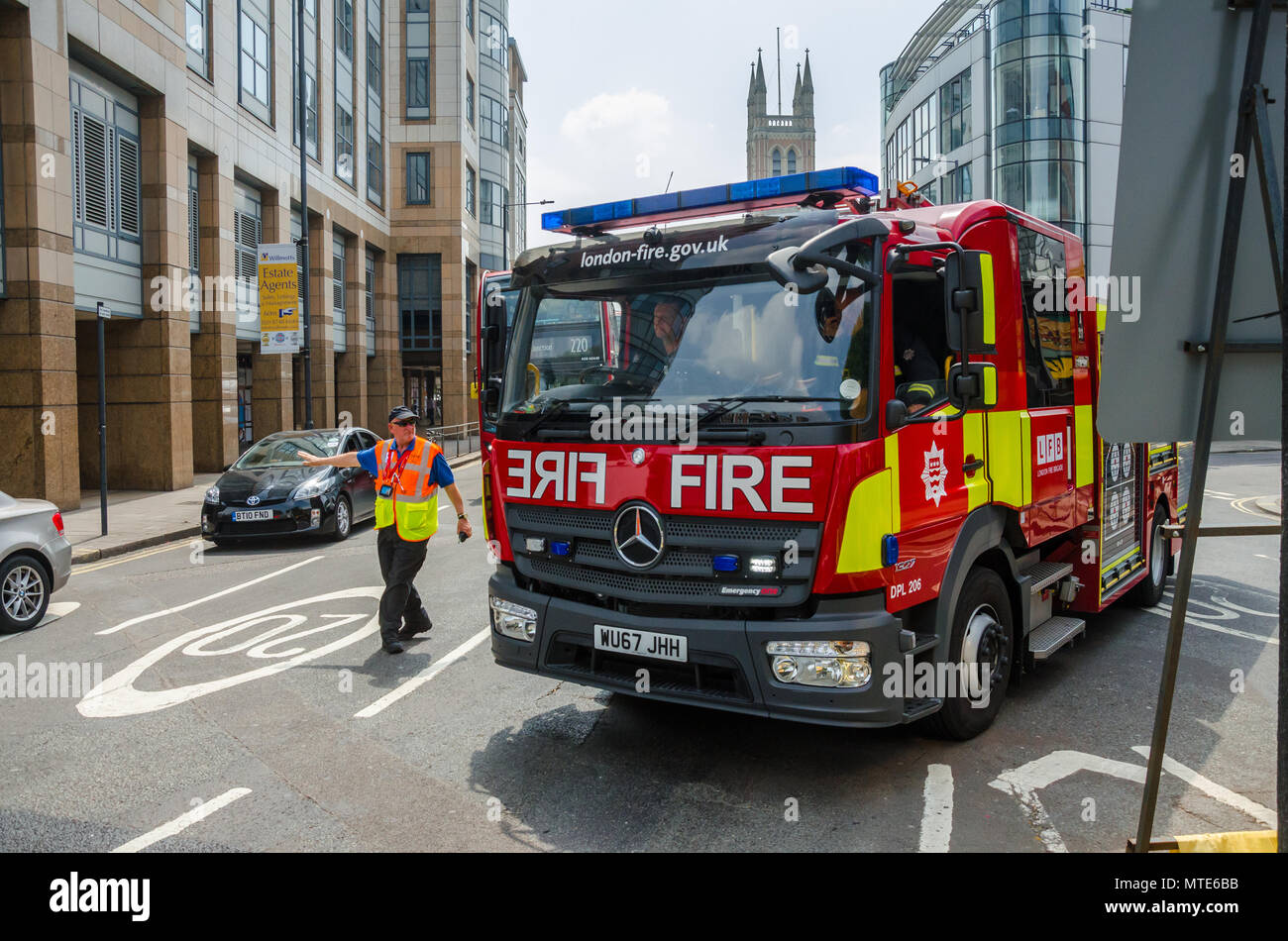 A fire engine belonging to the London Fire Brigade driving through Hammersmith with blue lights and siren blaring. Stock Photo