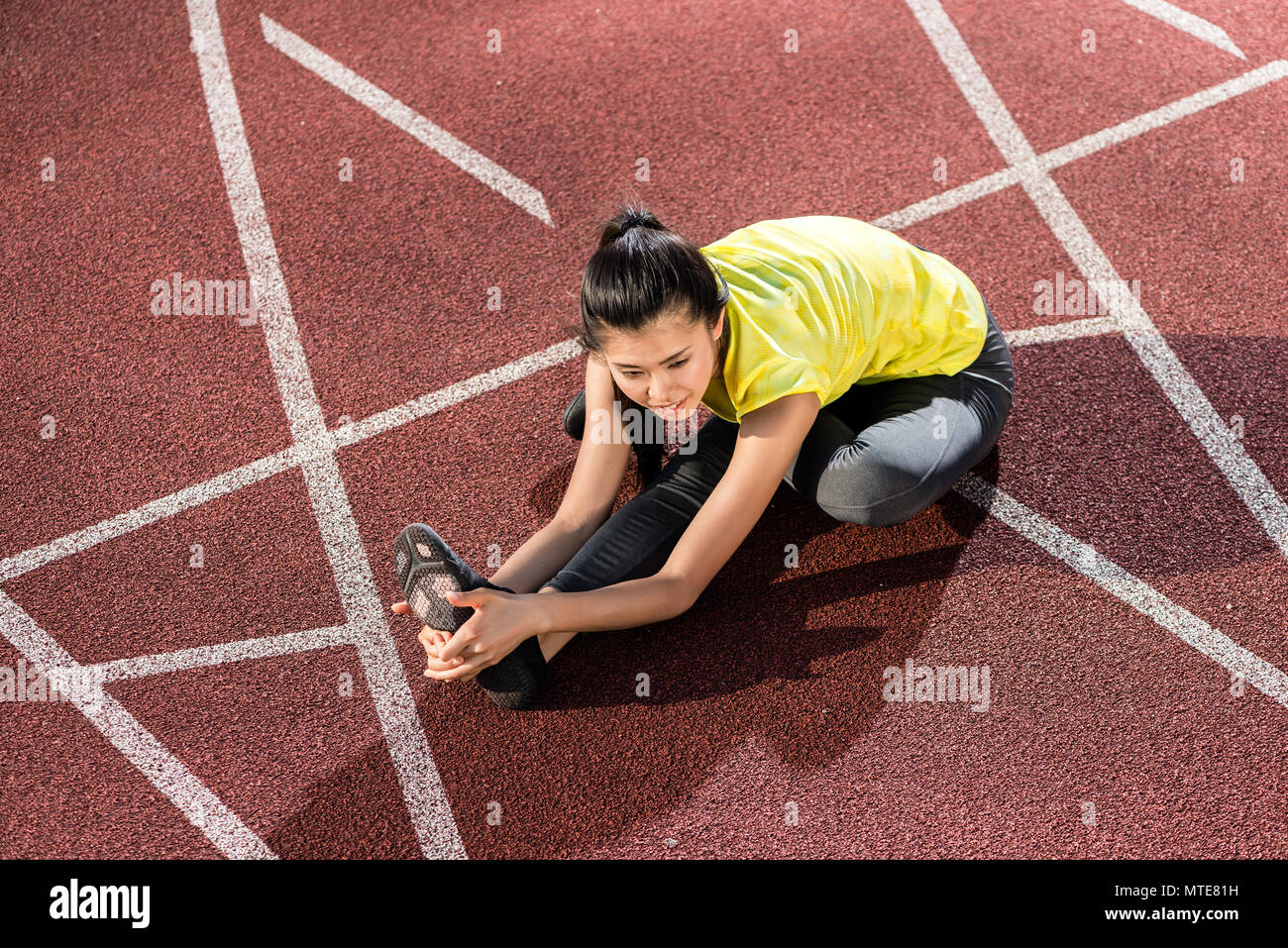 Woman sprinter doing warm up exercise before sprint Stock Photo