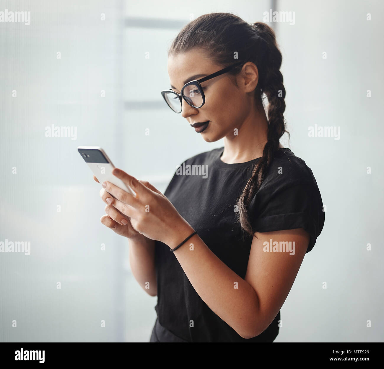 Young brunette girl with glasses and black lipstick holding mobile phone  Stock Photo - Alamy