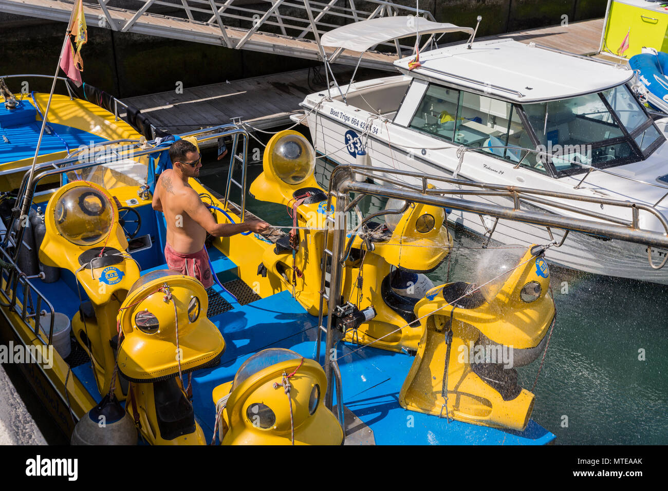 Man washing down BOB diving suits on a tour boat in Puerto Colon marina, Playa de Las Americas, Tenerife, Canary Islands, Spain Stock Photo