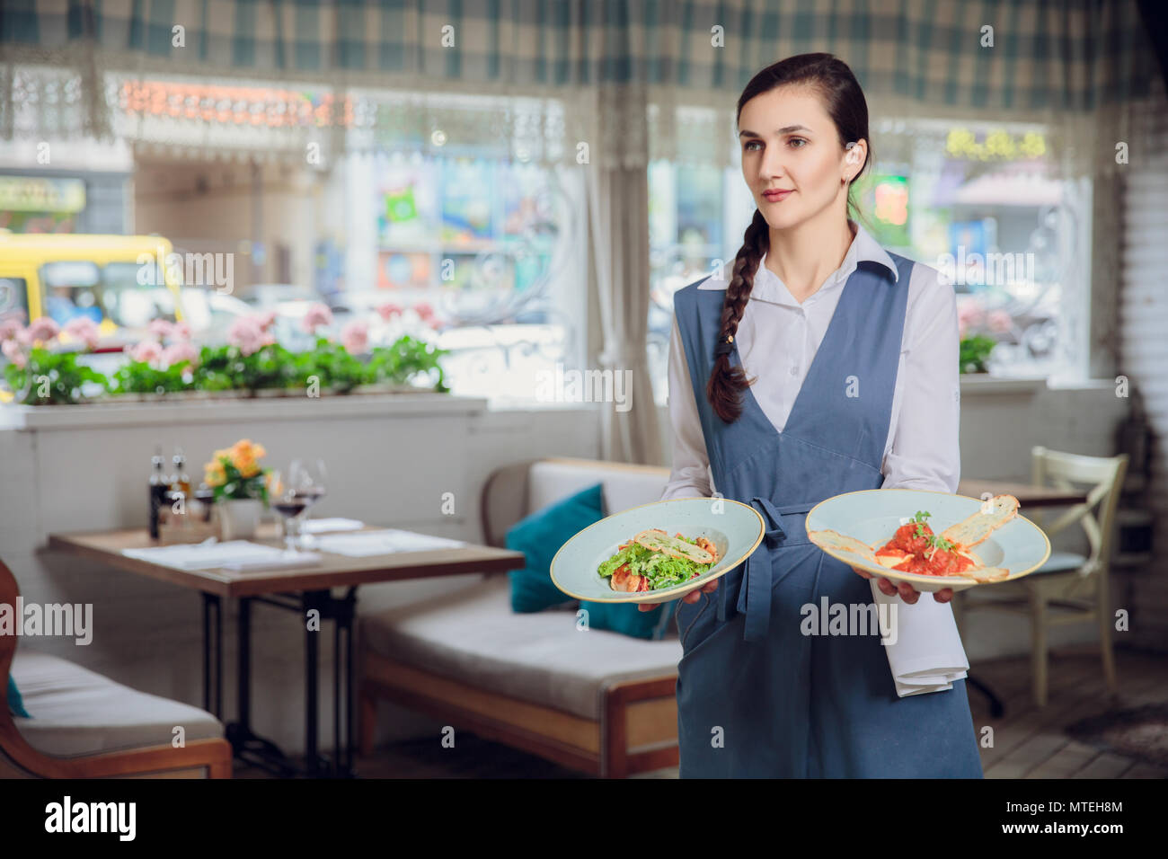 Waitress is carrying two plates with restautant delicious dishes
