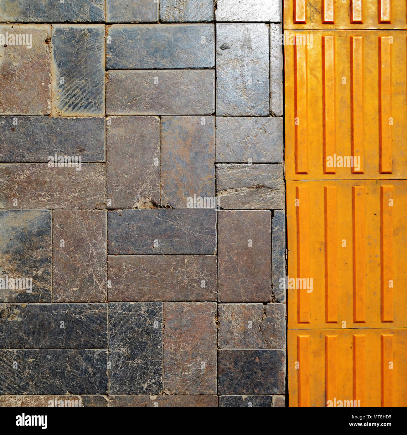 Granite pavement and yellow plastic pavement. Texture. Stock Photo