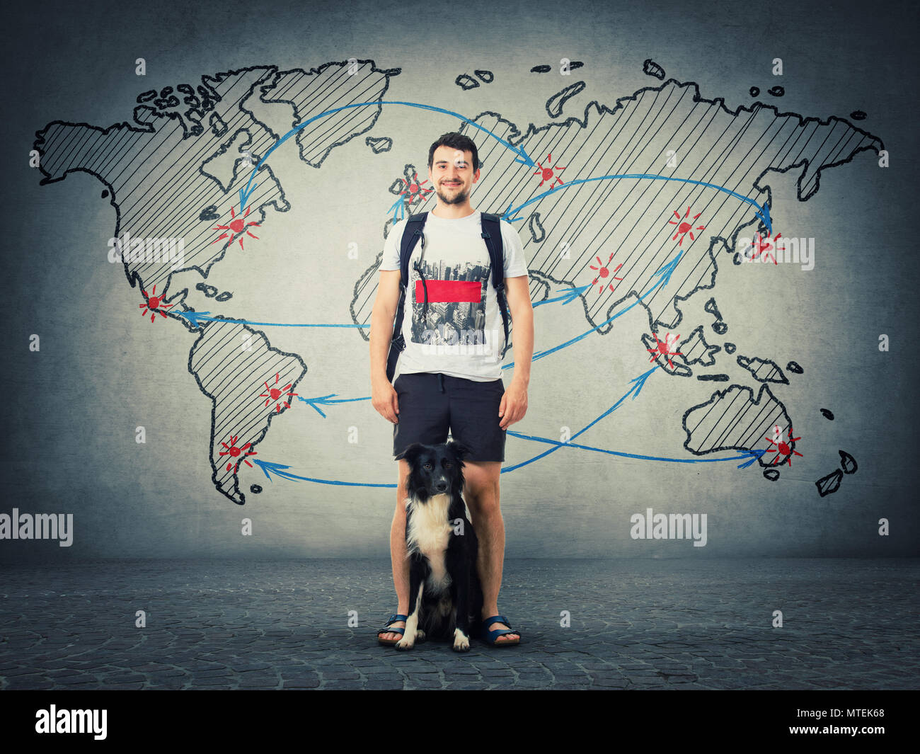 Happy guy carrying a backpack and his border collie dog ready for holiday trip isolated on grey wall with drawn world map and destinations. Friendship Stock Photo