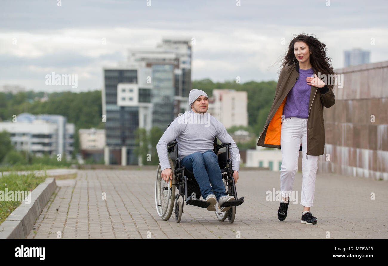 Happy couple disabled young man in a wheelchair with young woman