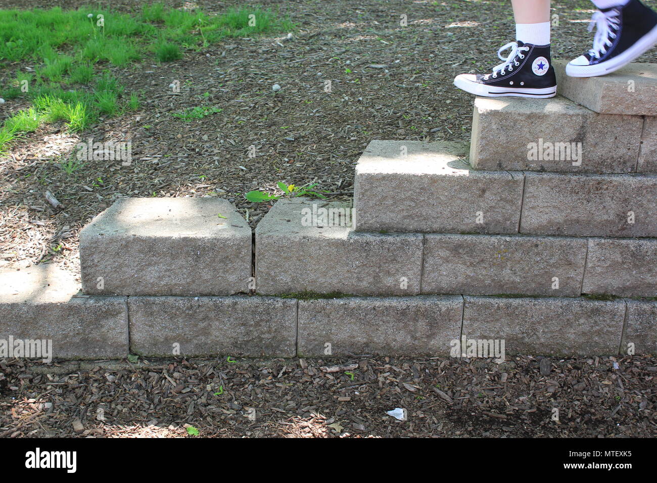 Teenaged girl walking up and down the stairs wearing white socks and a pair of black converse sneaker high-tops. Stock Photo