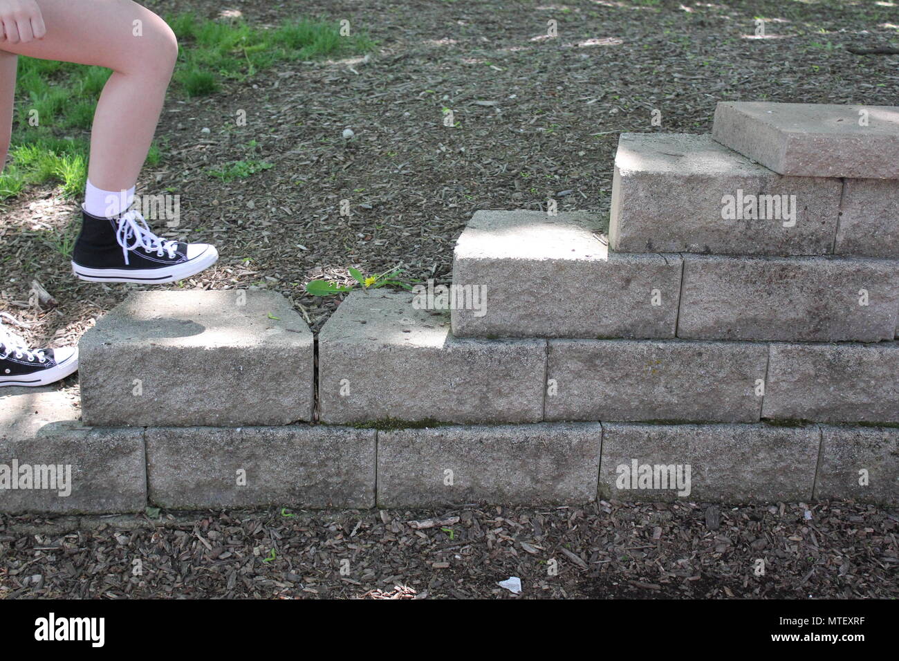 Teenaged girl walking up and down the stairs wearing white socks and a pair of black converse sneaker high-tops. Stock Photo