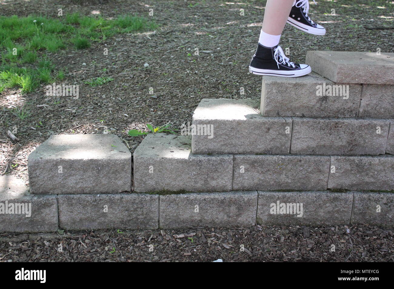 Teenaged girl walking up and down the stairs wearing white socks and a pair of black converse sneaker high-tops. Stock Photo