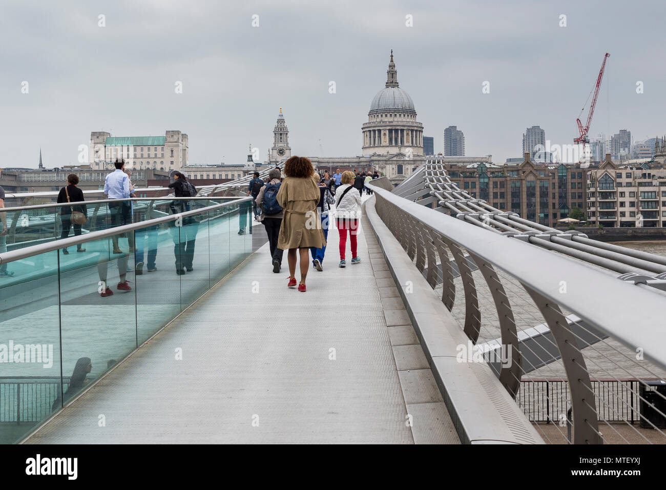 People walking across Millennium Bridge in London, with St Paul's Cathedral in background Stock Photo