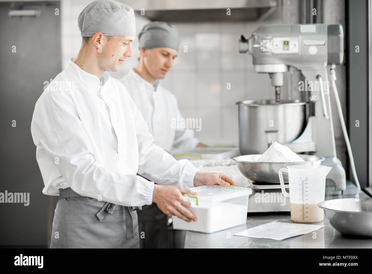 Two male confectioners preparing ingredients for baking standing at the manufacturing Stock Photo