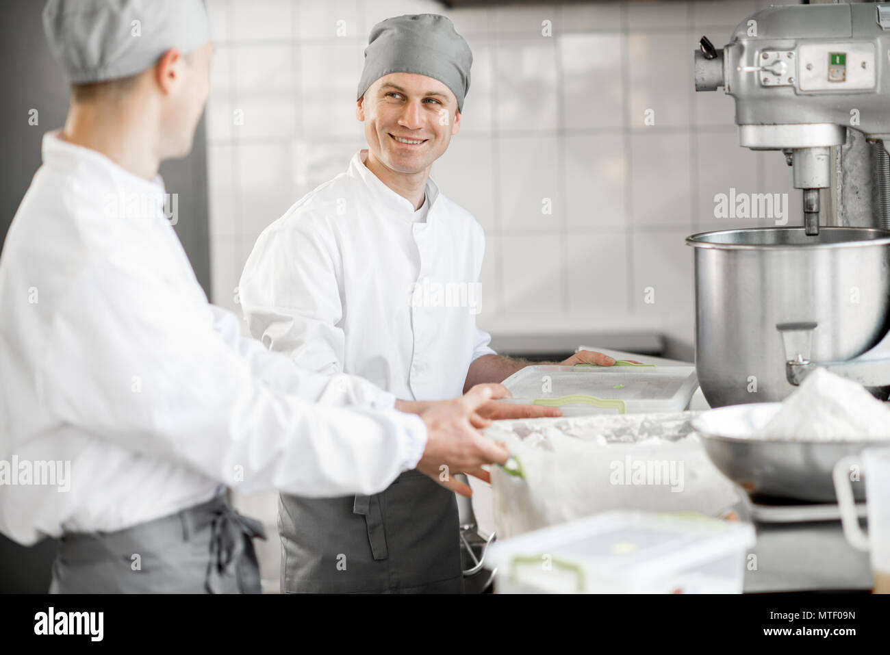 Two male confectioners preparing ingredients for baking standing at the manufacturing Stock Photo