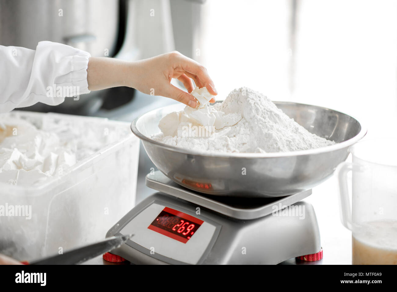 Weighing flour for baking with professional scales at the manufacturing, close-up view Stock Photo