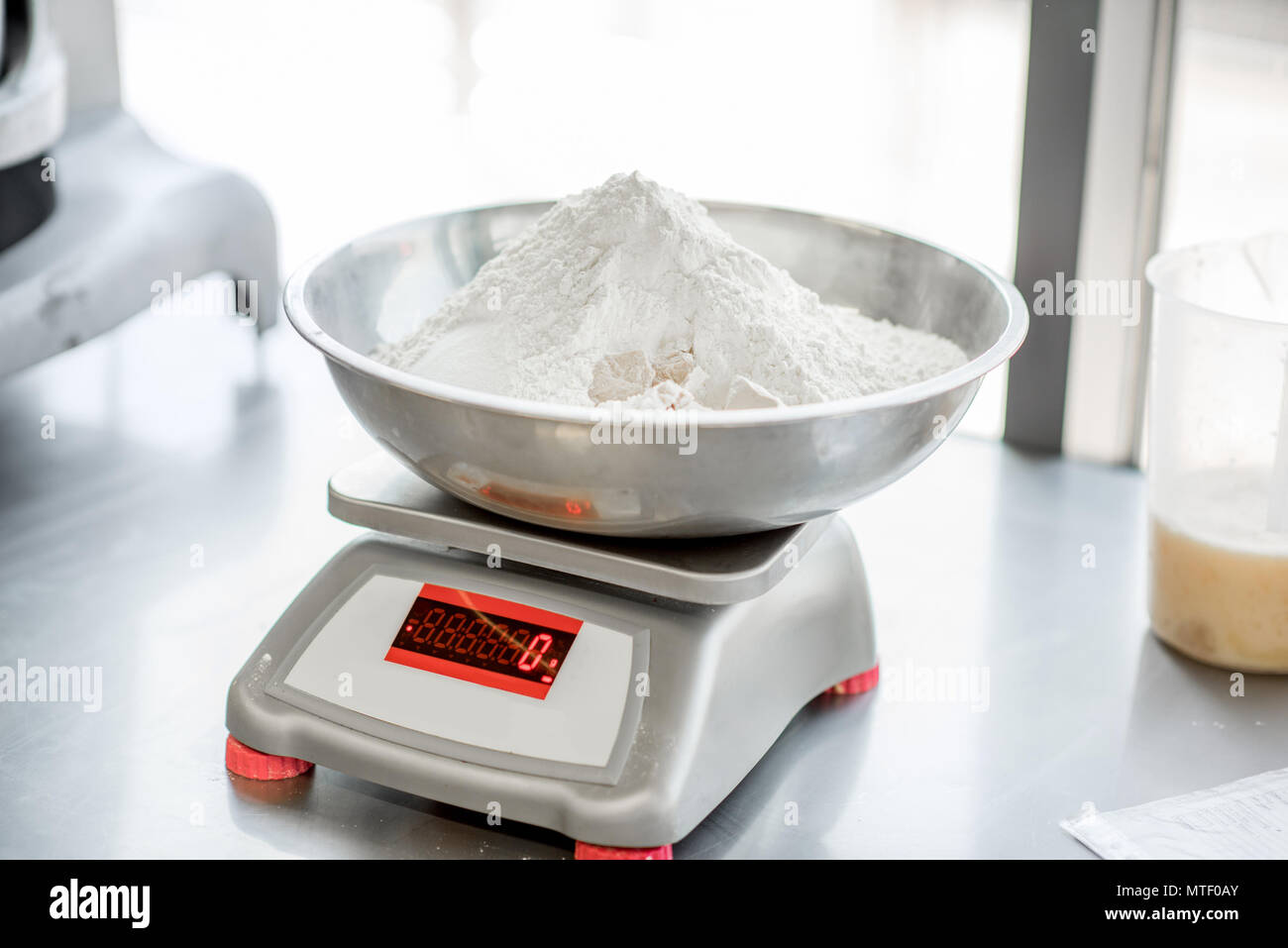 Weighing flour for baking with professional scales at the manufacturing, close-up view Stock Photo
