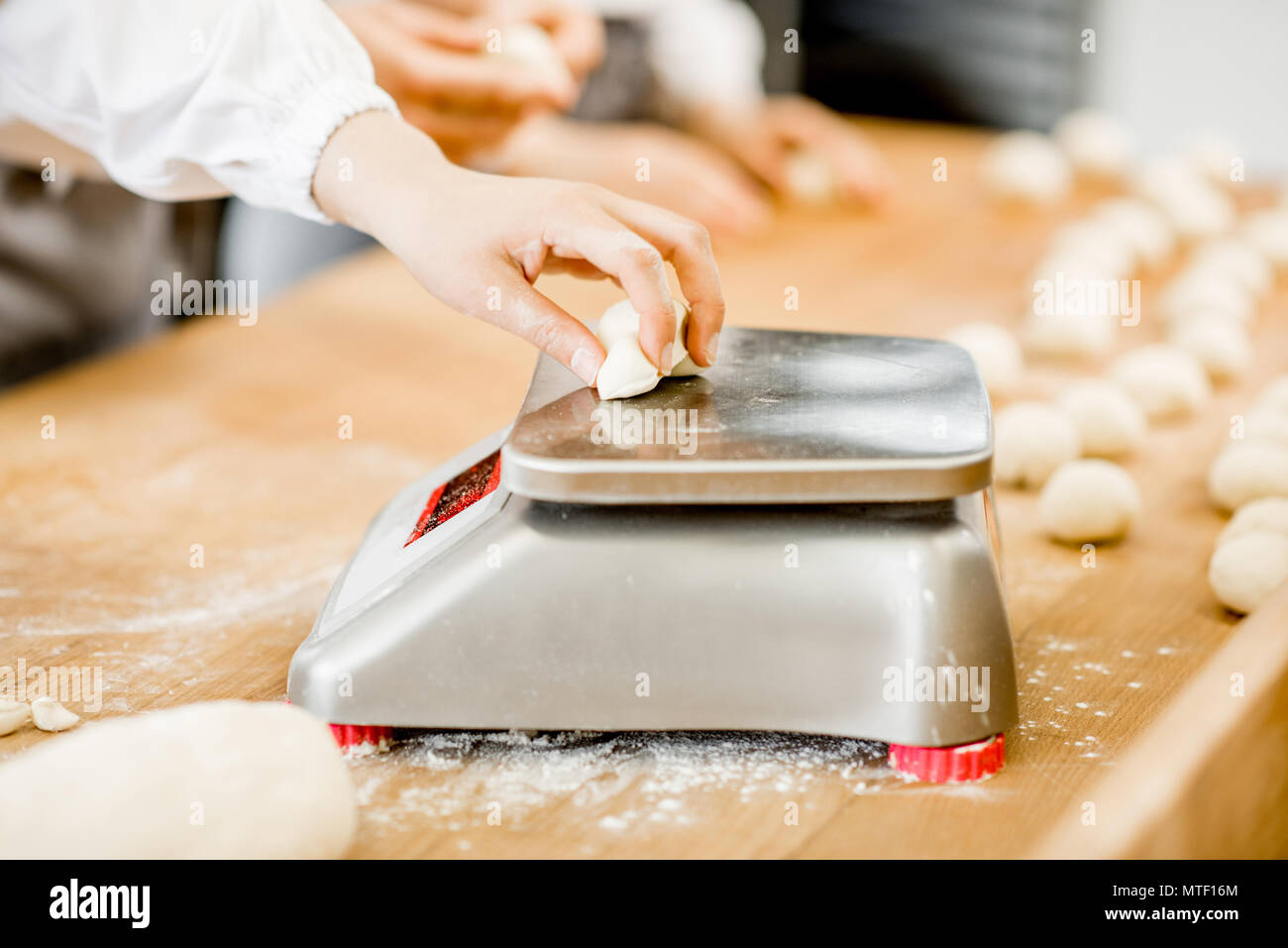 Baker weighing dough portions for baking buns at the manufacturig, close-up view Stock Photo