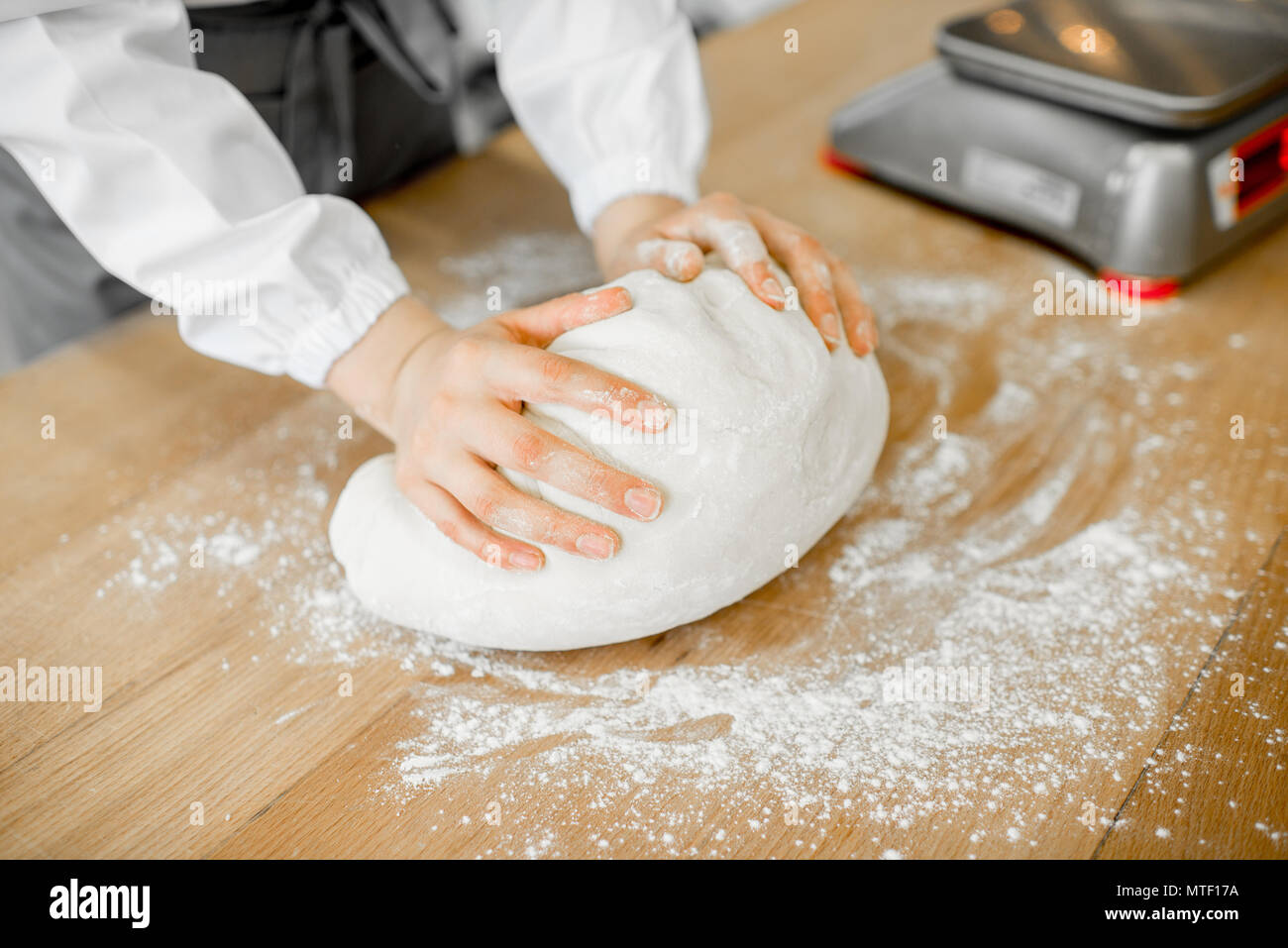 Baker forming daugh with hands for baking on the wooden table at the manufacturing Stock Photo