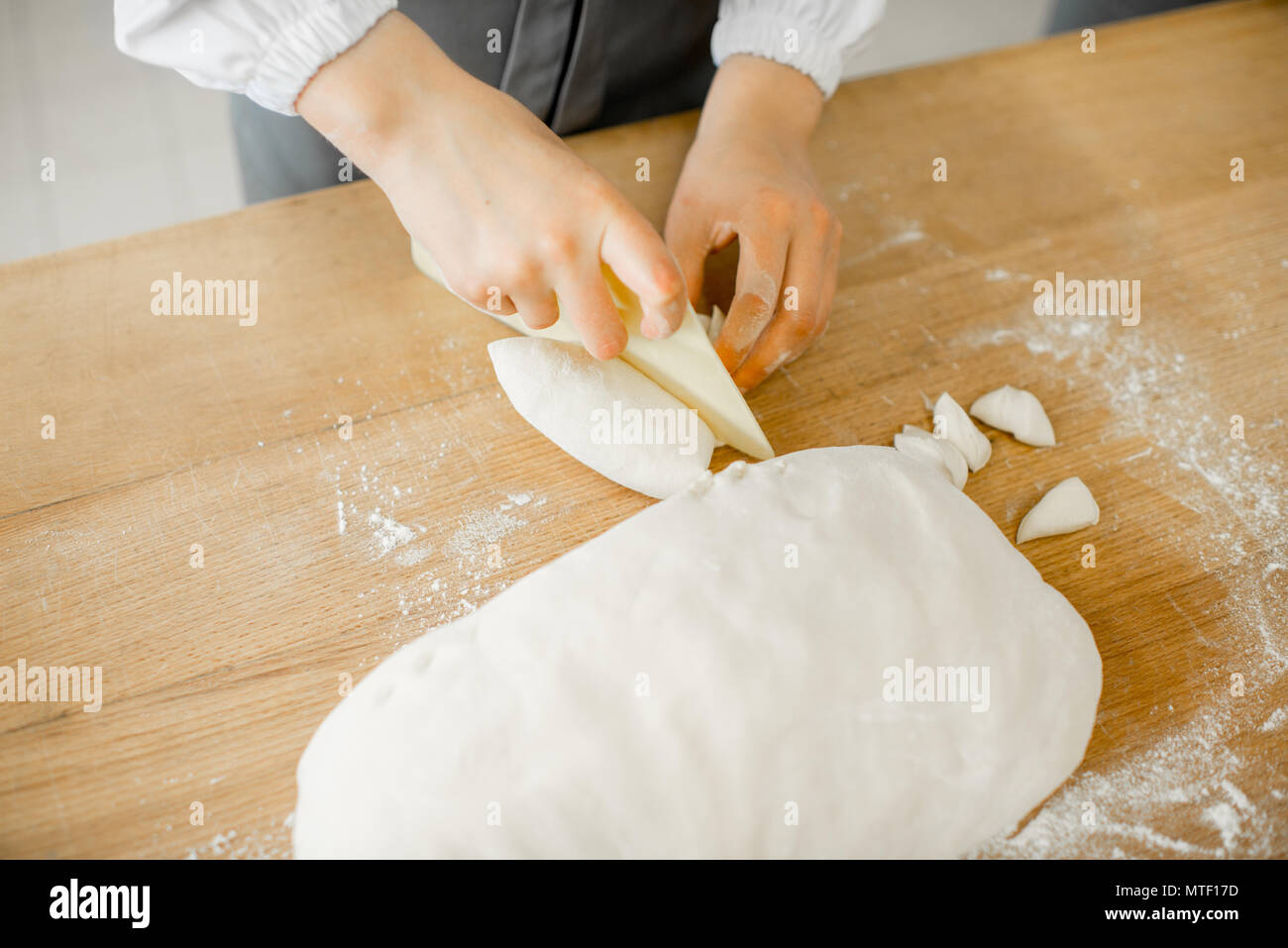Baker forming daugh with hands for baking on the wooden table at the manufacturing Stock Photo