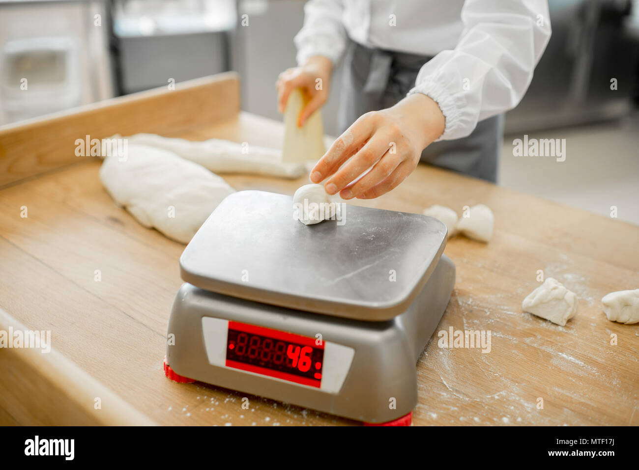 Baker weighing dough portions for baking buns at the manufacturig, close-up view Stock Photo