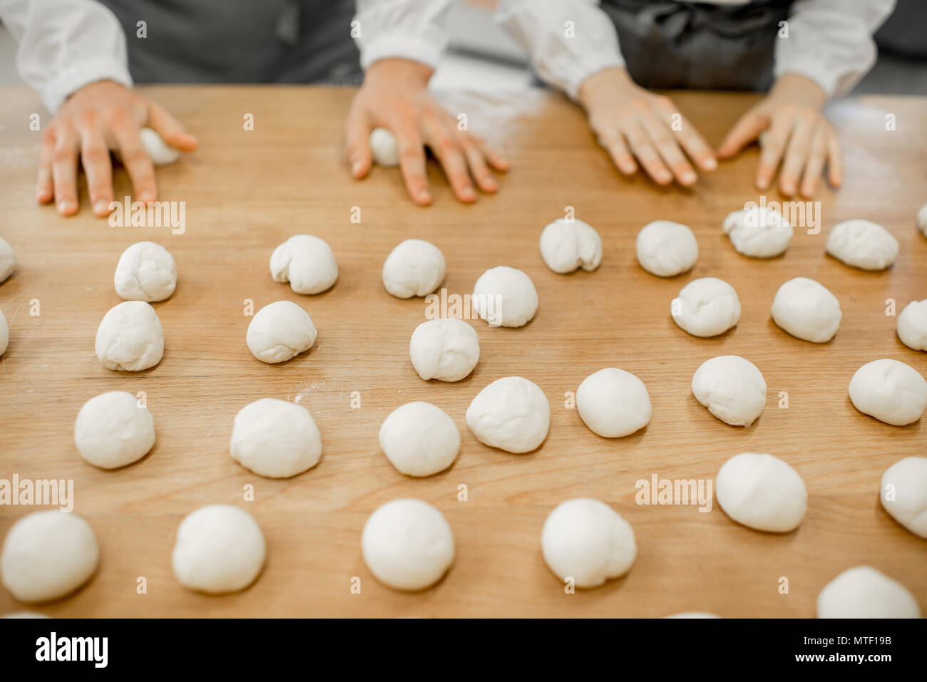 Forming daugh balls for baking buns on the wooden table at the manufacturing Stock Photo