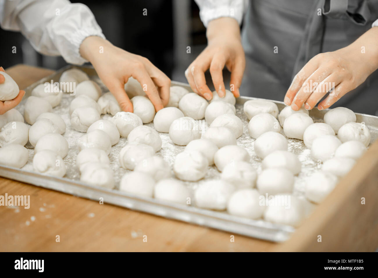 Forming daugh balls for baking buns on the wooden table at the manufacturing Stock Photo