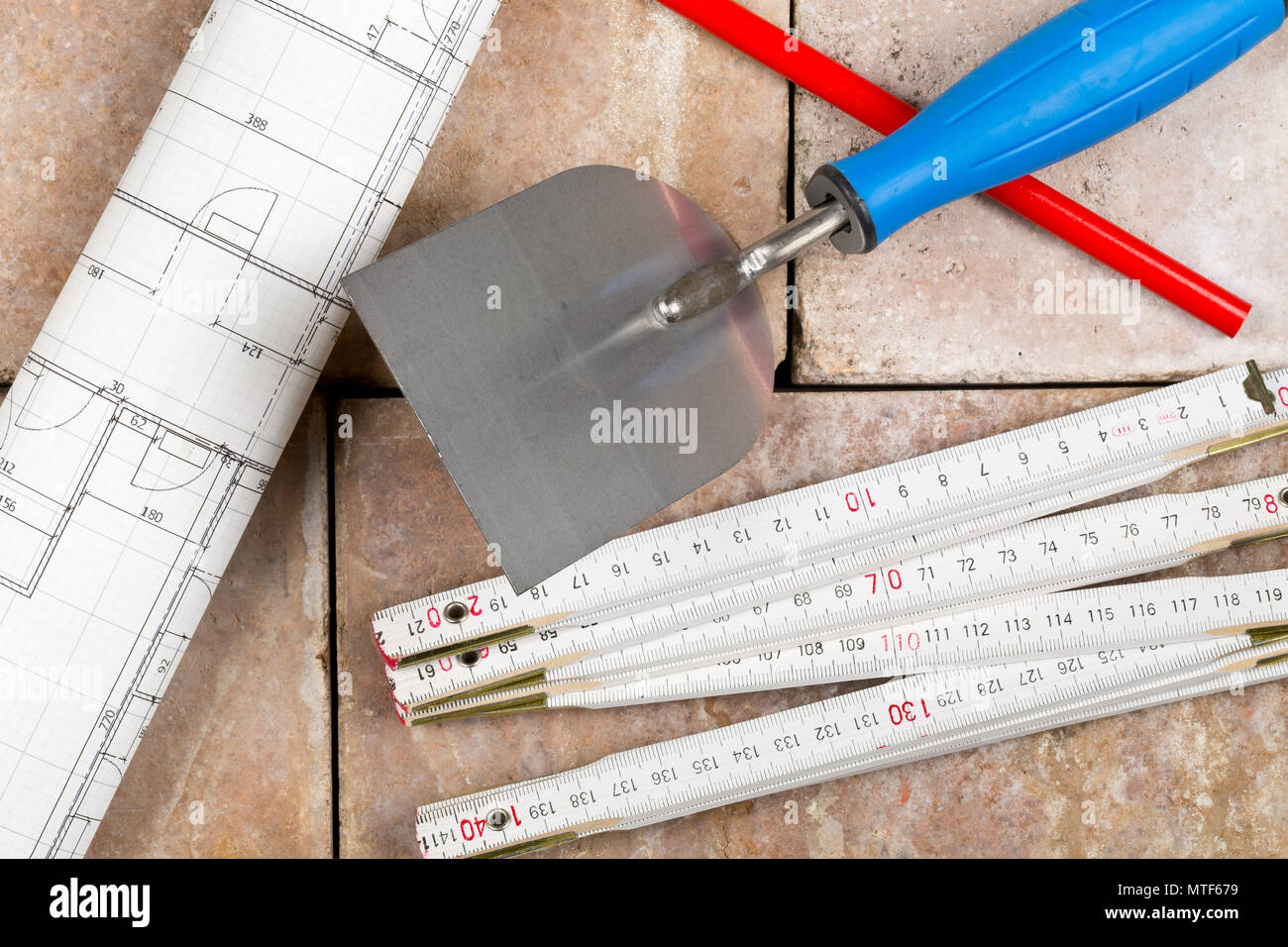 Trowel with folding rule, construction blueprint and pencil on bricks