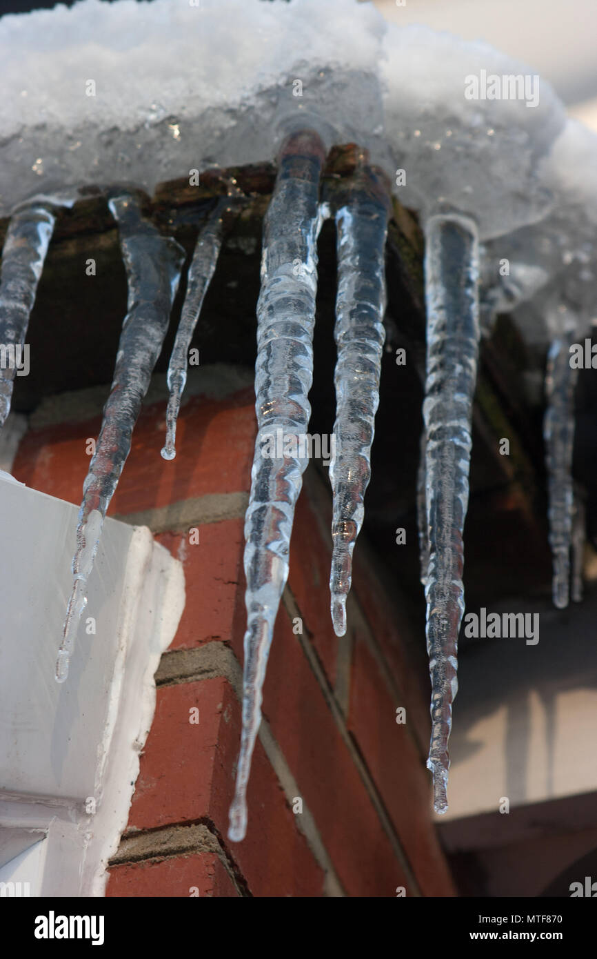 Icicles hanging from snow-covered roof of a house Stock Photo