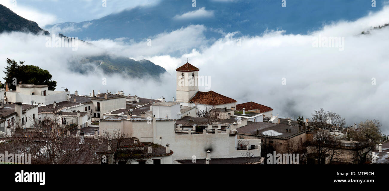 The Alpujarran village of Capileira, with its Catholic church shrouded in mist, high up in the Sierra Nevada mountains in Spain's Andalucia region. Stock Photo