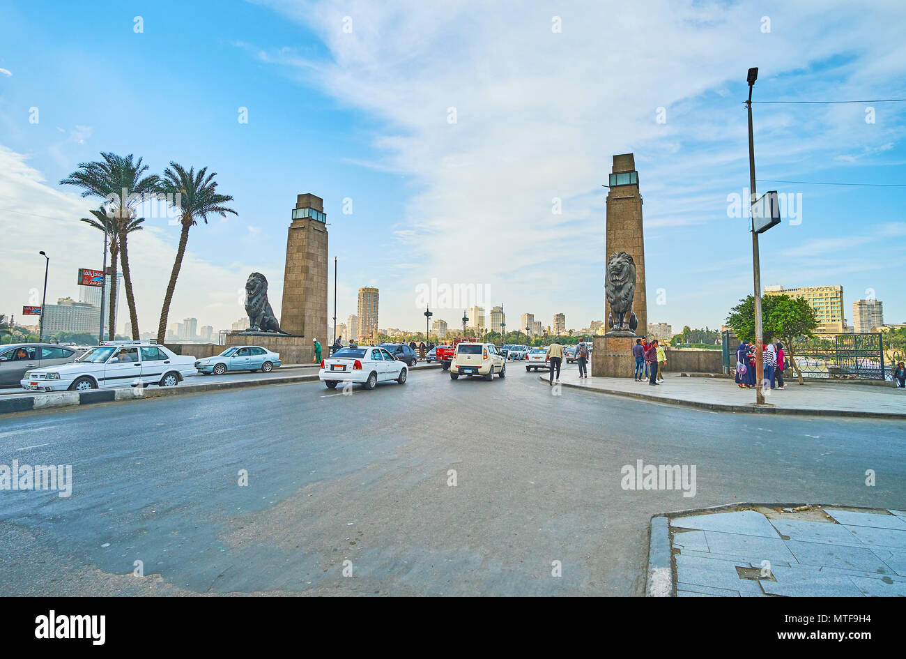 CAIRO, EGYPT - DECEMBER 24, 2017: The busy El Tahrir road, decorated with stone towers and sculprtures of lions at the entrance of Qasr El Nil bridge, Stock Photo