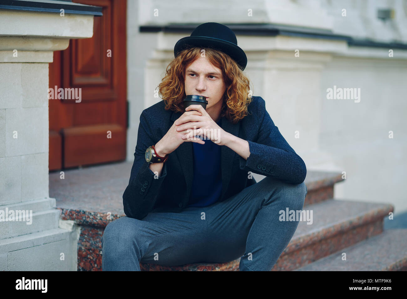Portrait Of Young Reddish Man With Long Curly Hair Sitting On