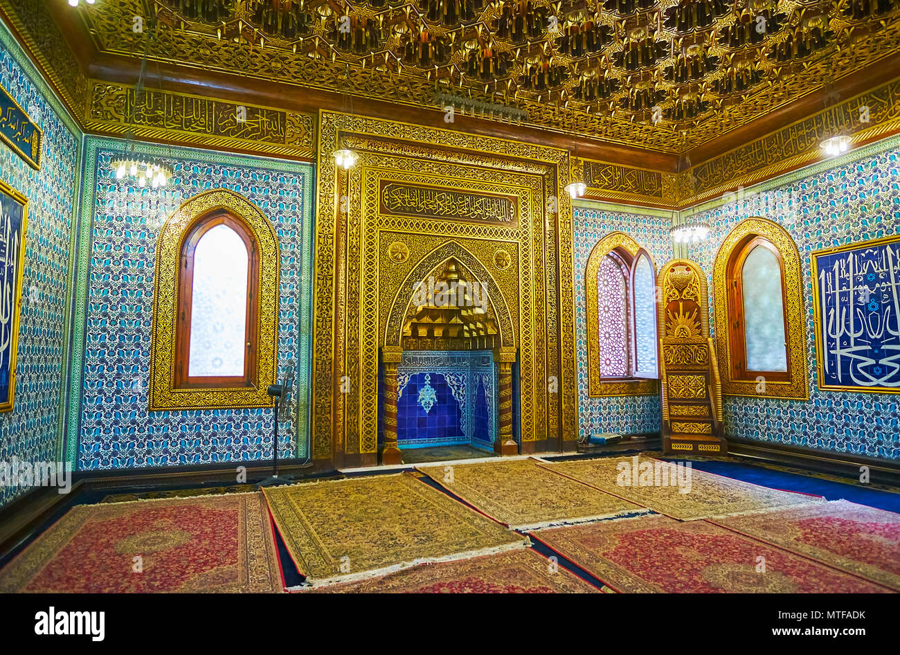 CAIRO, EGYPT - DECEMBER 24, 2017: Mihrab of Manial Palace mosque decorated with intricate golden patterns on carved wood, muqarnas in arch, bright blu Stock Photo