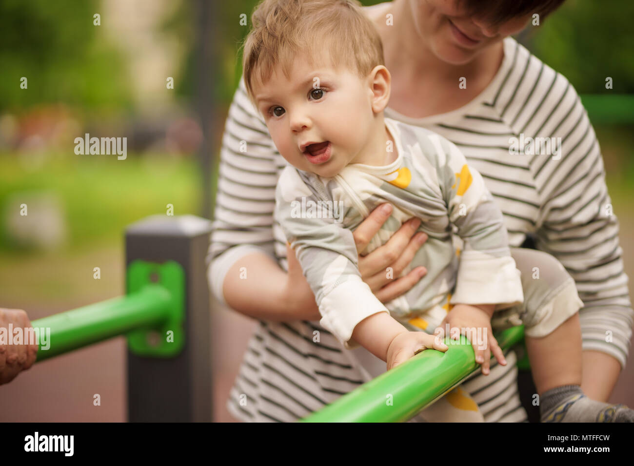 Concept: family values. Portrait of adorable innocent funny brown-eyed baby smiling and playing with his mom. Stock Photo