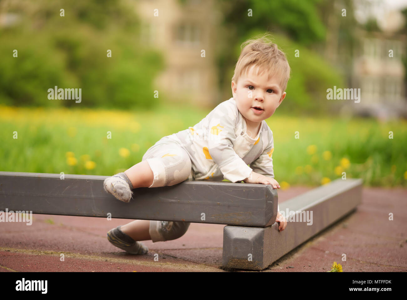 Concept: family values. Portrait of adorable innocent funny brown-eyed baby playing at outdoor playground. Stock Photo