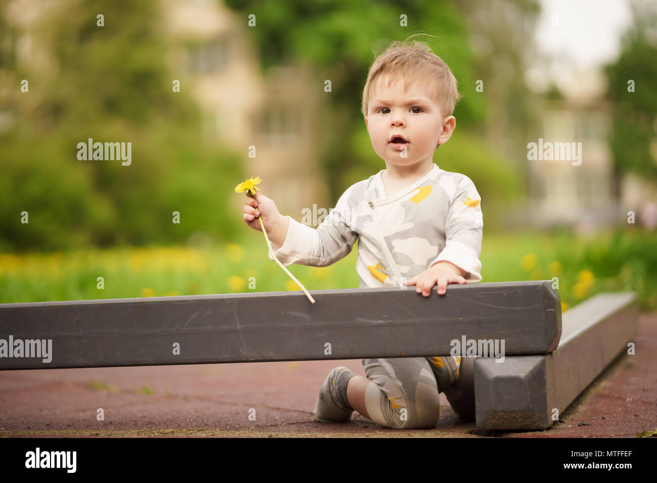 Concept: family values. Portrait of adorable innocent funny brown-eyed baby playing at outdoor playground. Stock Photo