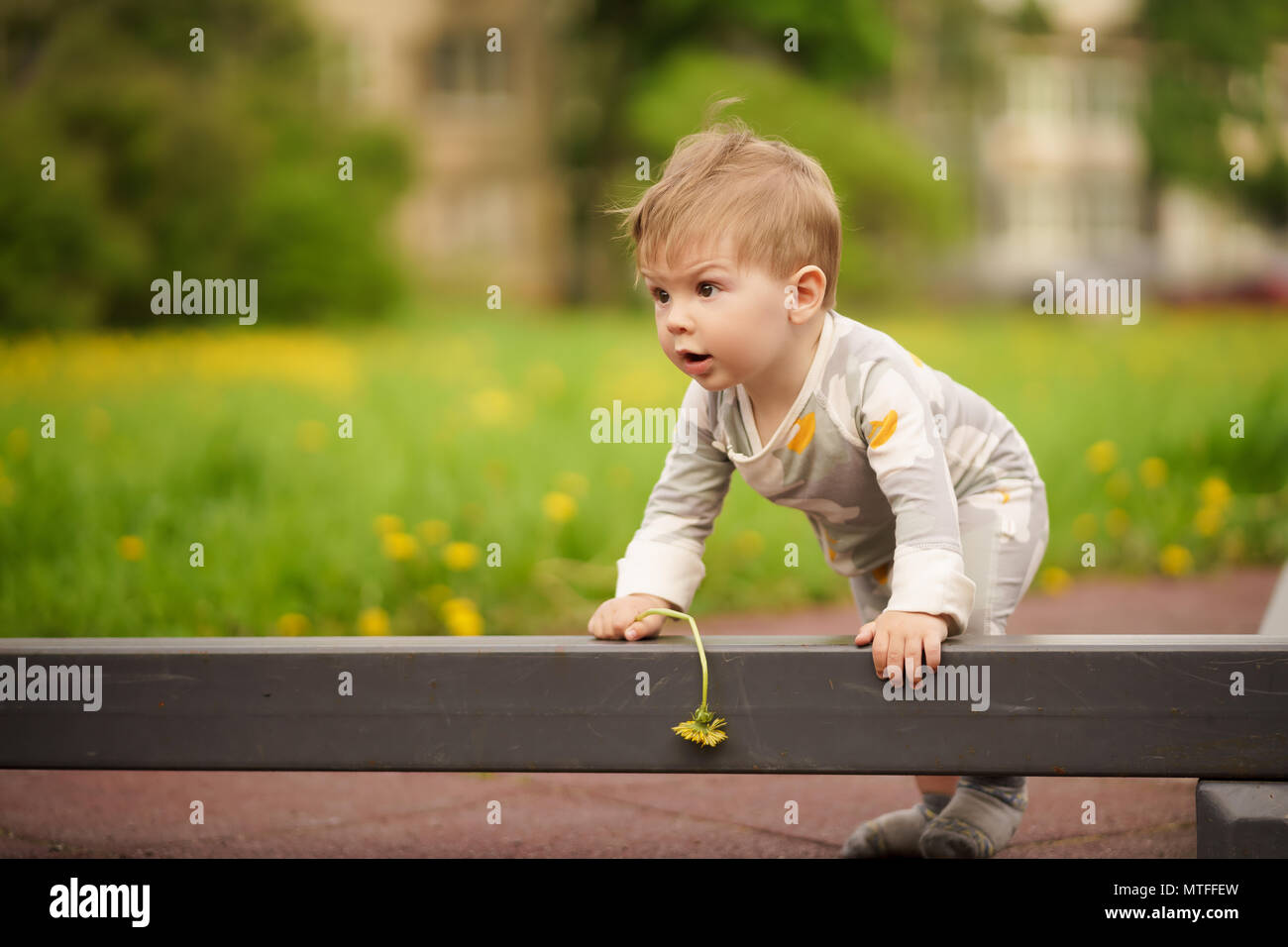 Concept: family values. Portrait of adorable innocent funny brown-eyed baby playing at outdoor playground. Stock Photo