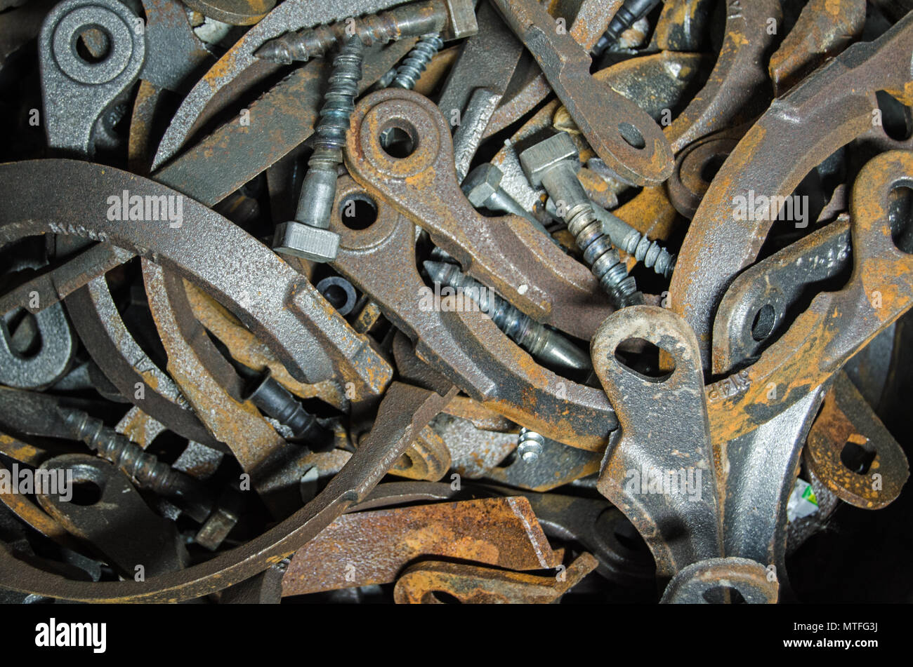 View of a pile of brackets and bolts quietly rusting in a bucket beside a civil engineering project. Stock Photo