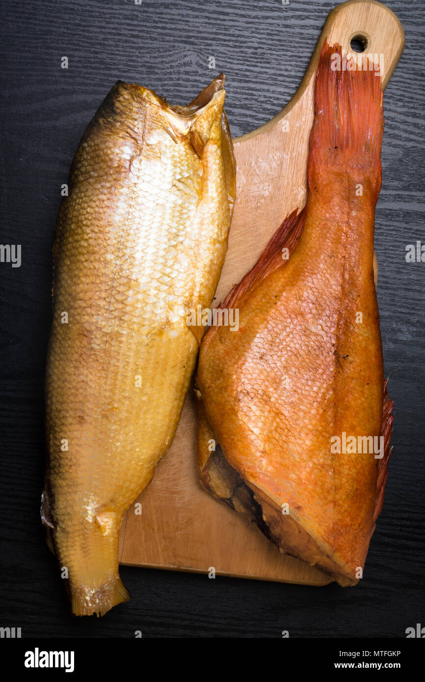 Smoked sig and perch on the black wooden table in the board Omega 3